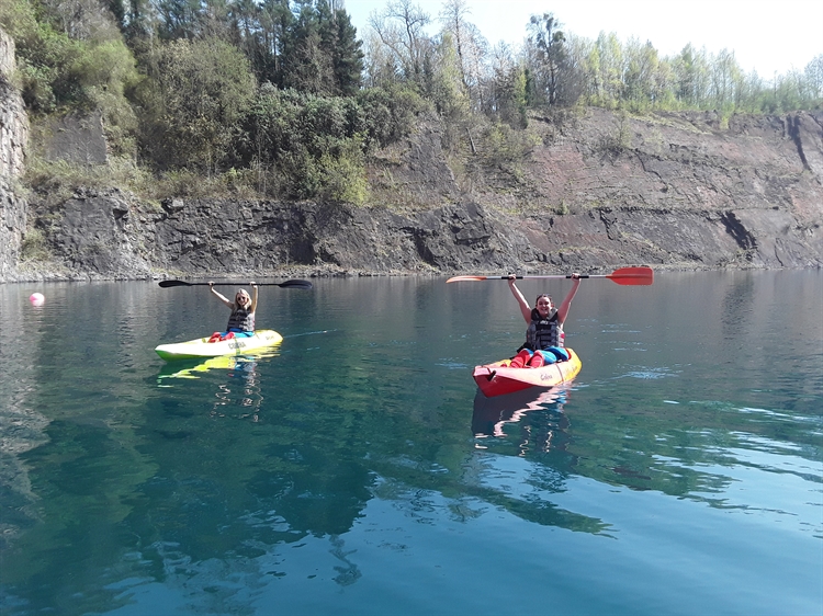 Two Kayakers Holding up Paddles